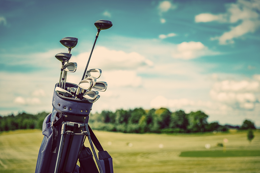 Golf equipment bag standing on a course. Summer sport and activity. Golf clubs close-up.